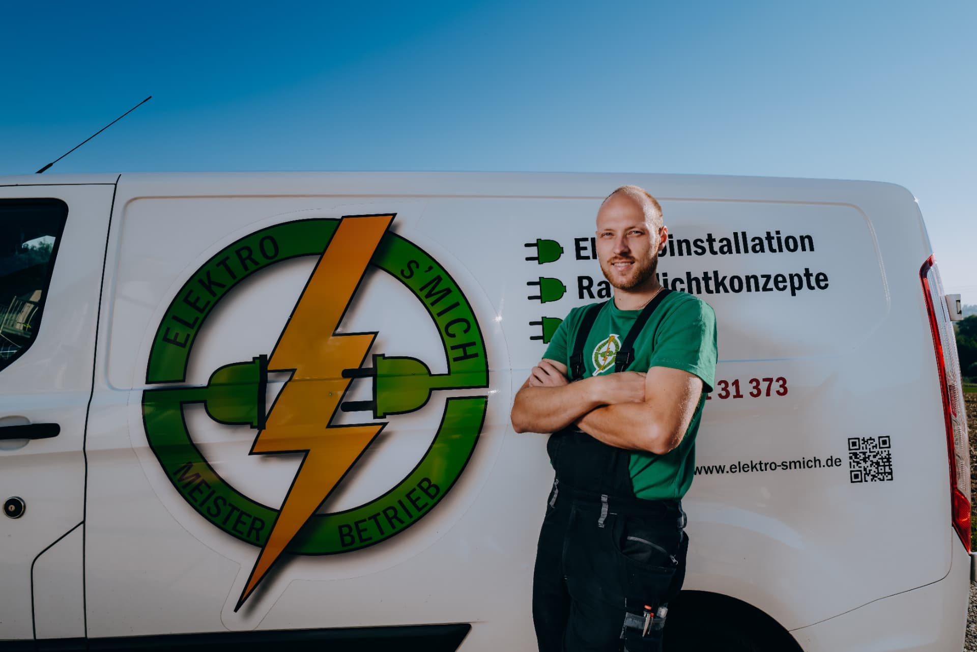 Teammitglied von Elektro-s'Mich vor dem Firmenfahrzeug