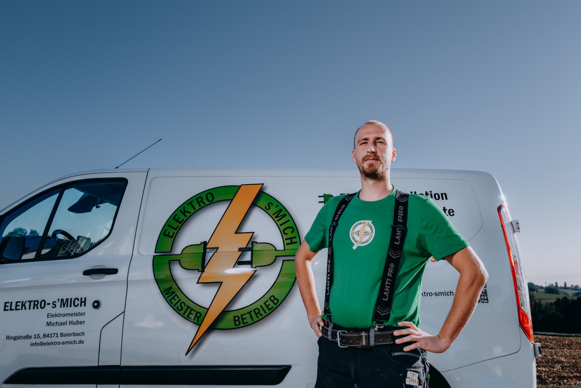 Teammitglied von Elektro-s'Mich vor dem Firmenfahrzeug