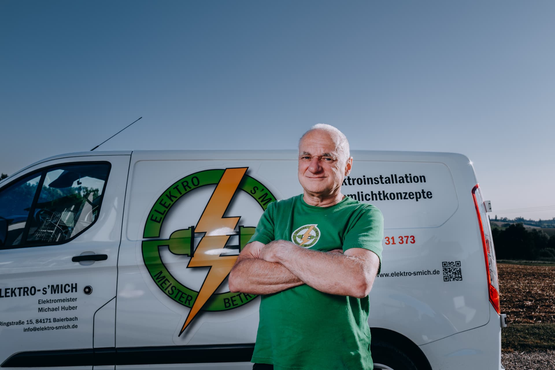 Teammitglied von Elektro-s'Mich vor dem Firmenfahrzeug