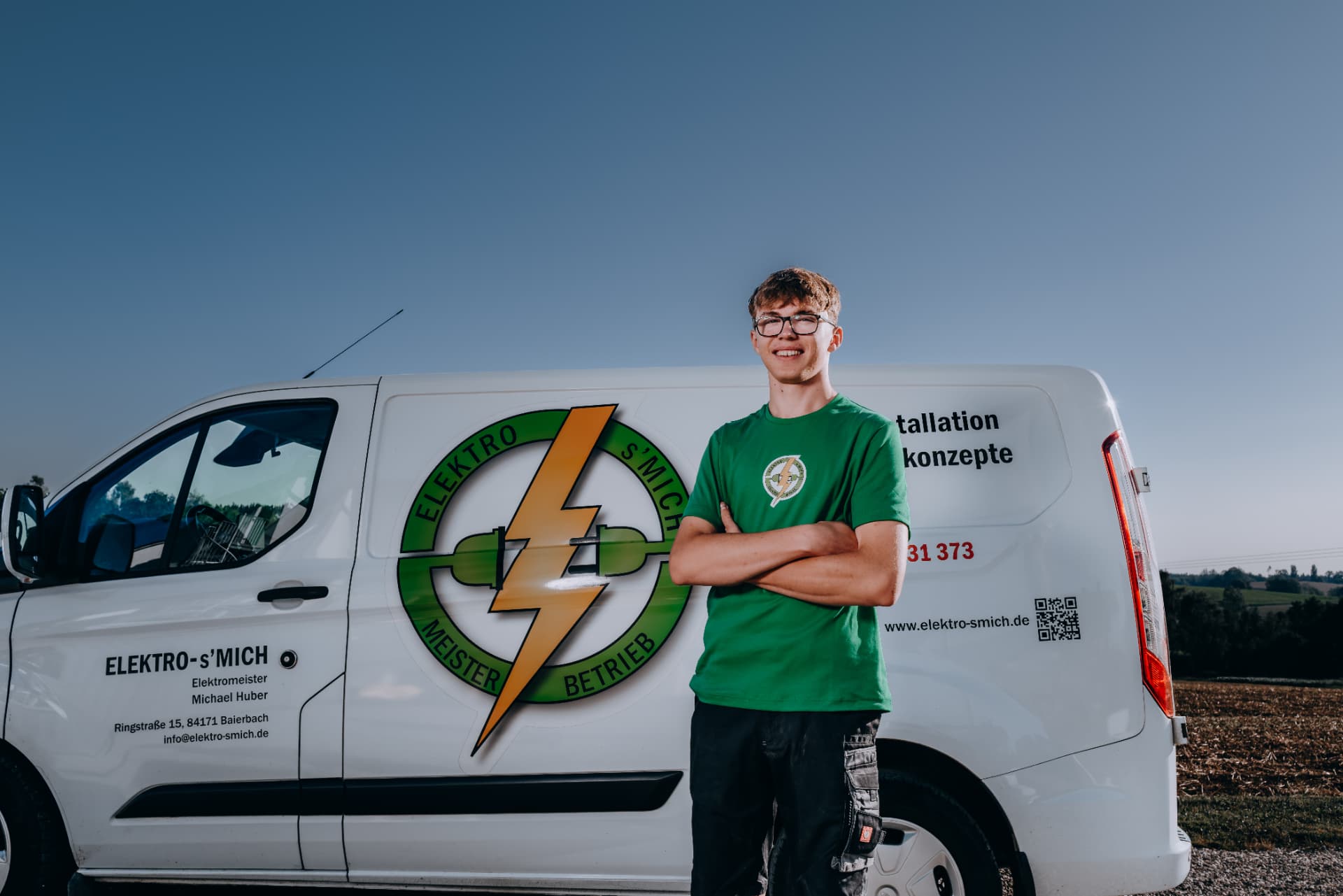 Teammitglied von Elektro-s'Mich vor dem Firmenfahrzeug