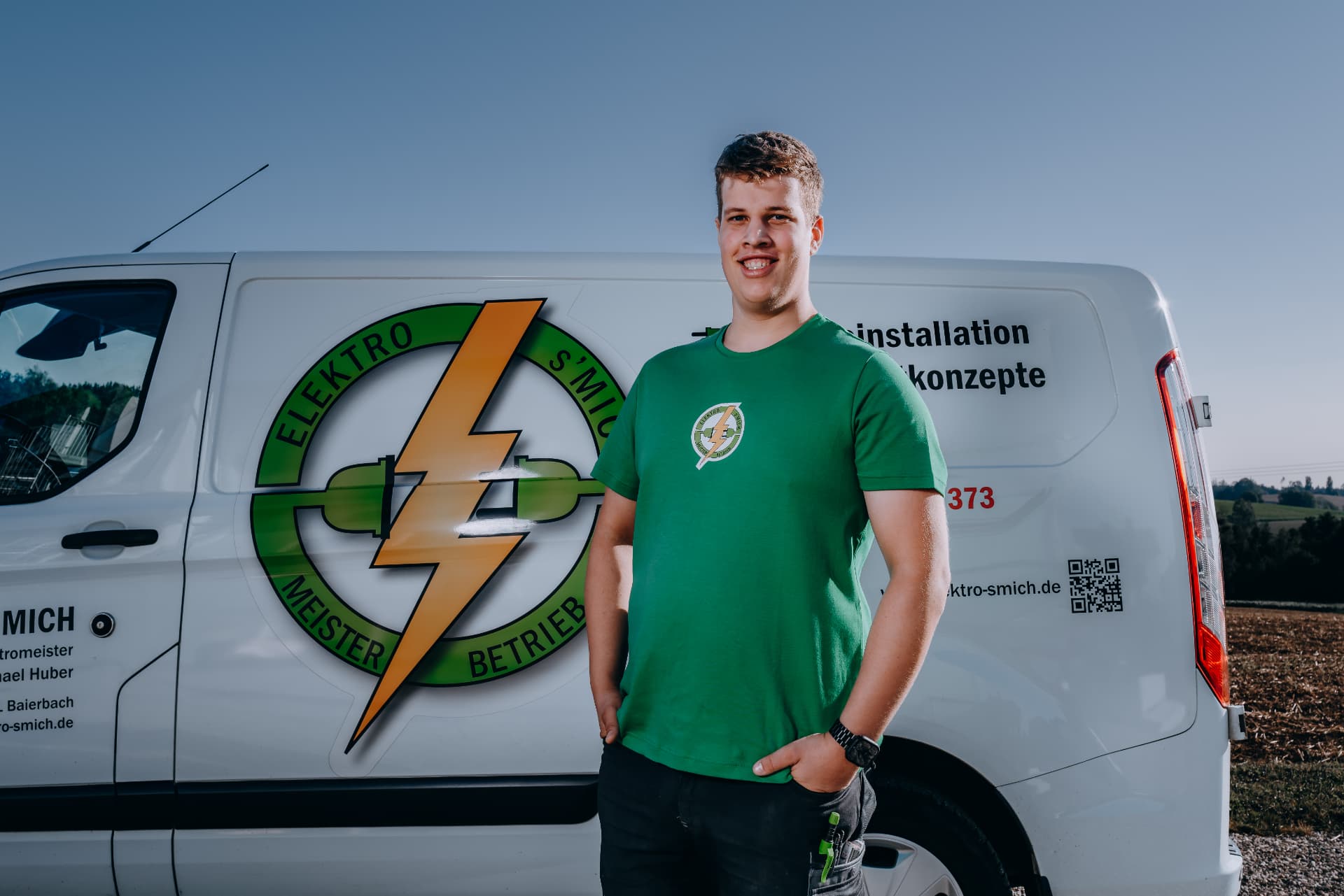Teammitglied von Elektro-s'Mich vor dem Firmenfahrzeug
